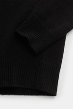 Close-up of the sleeve and hem of the Stone Island Half-zip jumper 'Lambswool' black, showing its elasticated ribbed bands and fine knit texture from a top-down perspective. A stylish essential for colder months: This timeless half-zip jumper by STONE ISL