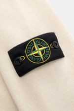 Stone Island Half-zip jumper 'Lambswool' cream shown in close-up from the side, highlighting the black patch with embroidered compass badge and embossed buttons on soft wool blend knitwear. A stylish essential for colder months with contrasting knit strip