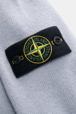 Stone Island Half-zip jumper 'Lambswool' smoky blue shown in close-up from above, highlighting the signature compass badge with embossed buttons on a soft wool blend. A stylish essential for colder months with knitwear in wool and microfibre, soft feel, m