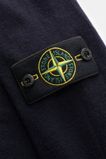 Close-up of the Stone Island Troyer black showing the brand-typical compass badge on the upper arm, photographed from a top-front angle with visible fine knit pattern and soft texture.

Additional description:
<p>Comfort meets style: The STONE ISLAND quar