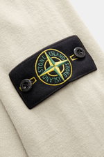 Close-up, top-down view of the Stone Island Half-Zip Jumper beige showing the black compass badge with green and yellow embroidery on soft virgin wool fabric.

<p>Comfort meets style: The STONE ISLAND half-zip jumper complements your autumn wardrobe with 