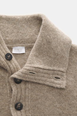 Nahaufnahme aus schräger Perspektive des 04651/ A trip in a bag Troyer 'Cloudy Wool' taupe meliert mit Troyer-Kragen, Knöpfen, Regular Fit, weichem Griff, mittelgrobem Strickbild, breiten Rippbündchen aus Schurwolle und Microfaser.