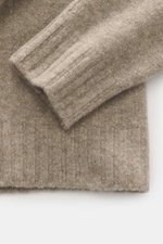 Nahaufnahme des Ärmels und Saums des 04651/ A trip in a bag Troyer 'Cloudy Wool' taupe meliert, Mix aus Schurwolle, weicher Griff, mittelgrobes Strickbild, Regular Fit, Troyer-Kragen mit Knöpfen, breite Rippbündchen.