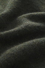 Nahaufnahme der dunkelgrün melierten Stoffstruktur des 04651/ A trip in a bag Troyer 'Cloudy Wool' mit weichem Griff, mittelgrobem Strickbild, Regular Fit, Troyer-Kragen mit Knöpfen und breiten Rippbündchen.