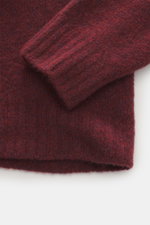 Nahaufnahme des Ärmelbündchens vom 04651/ A trip in a bag Troyer 'Cloudy Wool' dunkelrot meliert, Regular Fit, weicher Griff, mittelgrobes Strickbild, Troyer-Kragen mit Knöpfen, breite Rippbündchen, Mix aus Schurwolle und Microfaser.