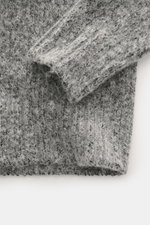 Nahaufnahme von Ärmel und Saum des 04651/ A trip in a bag Troyer 'Gritty' grau meliert, weicher Griff, voluminöses Strickbild, Mix Baumwolle und Alpakawolle, Regular Fit, hoher Rippstrickkragen mit Zipper, breite Rippbündchen, fotografiert von oben.