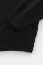 Nahaufnahme von Ärmel und Saum des schwarzen 04651/ A trip in a bag Cashmere Troyer 'Extreme' Slim Fit, reiner Cashmere, feines Strickbild, Troyer-Kragen mit Reißverschluss, sehr weicher Griff, flexible Rippbündchen.