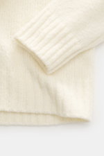Nahaufnahme des Ärmels und Bunds vom 04651/ A trip in a bag Troyer 'Molly' creme mit weicher Bouclé-Struktur, mittelfeinem Strickbild, Slim Fit und flexiblen Rippbündchen.