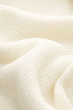 Cremefarbene Detailaufnahme des weichen Bouclé-Stricks des 04651/ A trip in a bag Troyer 'Molly' mit mittelfeinem Strickbild.
