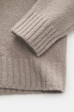 Nahaufnahme von Ärmelsaum und Bund des 04651/ A trip in a bag Troyer 'Molly' taupe in Bouclé-Struktur, weicher Merinowolle, slim fit, von oben.