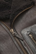Nahaufnahme einer geöffneten Belstaff Lammfelljacke 'Buxton Phoenix' braun mit edlem Lammfellkragen, robuster Reißverschluss und Rindslederbesatz.
