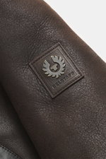 Nahaufnahme des tonalen Leder-Logos am Oberarm der braunen Belstaff Lammfelljacke 'Buxton Phoenix' aus edlem Lammfell.