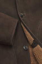 Close-up der Closed Lammfelljacke dunkelbraun aus geschmeidigem Lammleder mit weichem Griff, Drei-Knopf-Stil und sichtbarer Lammfell-Innenseite.