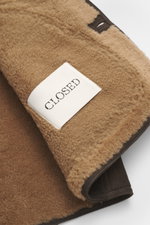 Nahaufnahme der flauschigen Innenseite der Closed Lammfelljacke dunkelbraun aus geschmeidigem Lammleder, Detail von Label und Saum.