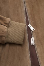 Nahaufnahme des Arma Veloursleder-Blouson 'Didier' taupe von schräg oben, zeigt feines Ziegenvelours, elastisches Rippbündchen und robusten Zwei-Wege-Zipper.