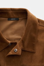 Nahaufnahme der braunen Tom Ford Velourslederjacke braun, Perspektive von oben auf Umlegekragen und verdeckte Druckknopfleiste aus feinstem Rindsveloursleder.