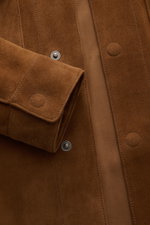 Nahaufnahme der Tom Ford Velourslederjacke braun aus feinstem Rindsveloursleder, zeigt Ärmel mit Druckknopf und verdeckte Druckknopfleiste.