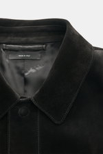Close-up front view of Tom Ford Velourslederjacke schwarz collar and upper button area, made from finest black suede leather with smooth texture and visible stitching, featuring a hidden snap button placket and soft shiny interior lining, photographed fro