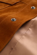 Close-up front detail of Tom Ford Suede jacket brown showing finest calfskin suede, snap button closure, and glossy inner lining from top-down view.