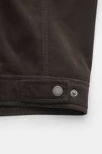 Nahaufnahme der dunkelbraunen Windsor Velourslederjacke 'Attilio' mit feinem Veloursleder, Druckknopf, Detail von Regular Fit, Umlegekragen, Zwei-Wege-Reißverschluss, schrägen Hüfttaschen, geschmeidigem Innenfutter und zwei Innentaschen, seitliche Perspek