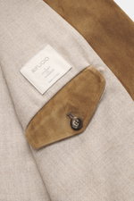 Rifugio Brown Suede Blazer close-up view from above showing the detailed soft lining, buttoned suede sleeve cuff, and brand label on beige fabric. RIFUGIO combines style with safari elements in this luxurious jacket made of supple suede leather blazer des