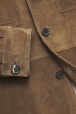Close-up front view of Rifugio Brown suede leather jacket showing soft suede texture, five-button placket, patch chest pockets, and sleeve cuffs with buttons.

<p>A statement of finest leather craftsmanship: The suede leather jacket by RIFUGIO impresses w