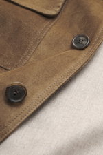 Close-up from above of the Rifugio Brown suede leather jacket showing details of supple suede, buttons, and stitching.

Description:  
<p>A statement of finest leather craftsmanship: The suede leather jacket by RIFUGIO impresses with its velvety-soft feel