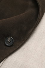 Nahaufnahme aus schräger Perspektive des Rifugio Veloursleder-Sakko dunkelbraun mit geschmeidigem Veloursleder, Knopf und feinem Schurwollfutter.