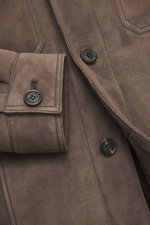 Nahaufnahme der Rifugio Lammleder-Jacke graubraun aus Veloursleder, mit Knöpfen, Manschetten und Brusttasche, seitlich fotografiert.