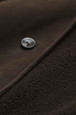 Nahaufnahme der Agnona Velourslederjacke dunkelbraun von innen mit weichem Shearling-Futter und geprägtem Metallknopf, Detailansicht.