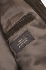Close-up interior view of the Windsor Velour leather blouson 'Borello' dark brown, showing soft goat velour leather, smooth lining, angled welt pocket, and a label highlighting finest chrome-free goat suede, featuring soft feel, light padding, slim fit, s