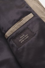 Close-up inside view of the Windsor Velour leather blouson 'Borello' taupe showing smooth lining, soft goat velour leather, angled welt pocket, and label, photographed from above. Features soft feel, light padding, slim fit, stand-up collar, two-way zippe