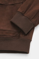 Nahaufnahme des Arma Veloursleder-Blouson 'Gwenno' dunkelbraun von schräg oben, feines Veloursleder, Regular Fit, Umlegekragen, Zwei-Wege-Reißverschluss, Hüfttaschen, elastische Rippstrickbündchen, geschmeidiger Futterstoff.