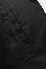 Nahaufnahme der schwarzen Ami Paris Daunenjacke mit wattiertem Kragen, glattem Microfaserstoff und paspelierter Tasche.