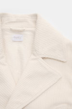Nahaufnahme der cremefarbenen 04651/ A trip in a bag Cord-Cabanjacke mit voluminösem Breitcord und Seersucker-Futter, Detail vom Reverskragen.