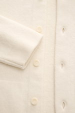 Close-up front view of the cream-colored 04651/ A trip in a bag Woll-Overshirt 'Boiled Blouson' showing buttons and cuff detail. <p>Boiled Blouson</p>