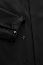 Black close-up image of the Golden Goose Overshirt 'M's Tailored Shirt Paolo W Camp' black, showing the front buttons and sleeve cuff with satin highlights, photographed from a top-down perspective. Uncomplicated, individual, GOLDEN GOOSE: This overshirt 