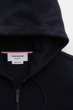 Nahaufnahme der Thom Browne Jacke navy von oben, Kapuze mit Tunnelzug, Zwei-Wege-Reißverschluss, reine Baumwolle, leicht griffige Struktur, Regular Fit.