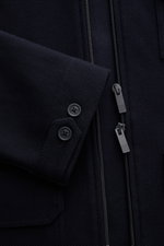 Nahaufnahme der Thom Browne Jacke navy von vorne, zeigt fein strukturierte Baumwolle, Zwei-Wege-Reißverschluss und Knopfärmel.