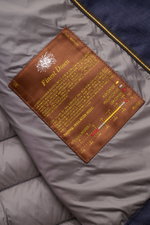 Close-up from above of the inside label on the Moorer Down jacket 'Alec' navy melange, showing quilted grey lining and brown tag with yellow text.

<p>This elegant quilted jacket 'Alec' by MOORER will see you through the changing seasons in style. The lig
