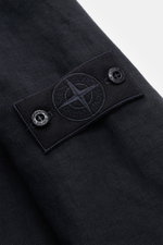 Nahaufnahme der Stone Island Jacke 'Ghost Piece' navy, Fokus auf tonal gehaltenes Ärmel-Badge aus Leinen-Mix mit Druckknöpfen.