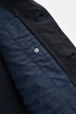 Nahaufnahme der Stone Island Jacke 'Ghost Piece' navy von innen, mit Leinen-Mix, Slim Fit, verdeckter Knopfleiste und tonalem Ärmelbadge.