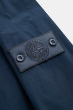 Stone Island Jacke 'Ghost Piece' dunkelblau, Nahaufnahme des Ärmel-Logos mit Knöpfen, hochwertige Microfaser, weicher Griff, Unconstructed Design.