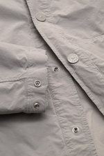 Stone Island Jacke 'Ghost Piece' hellgrau, Nahaufnahme der Druckknopfleiste, Ärmel mit Druckknopf, hochwertige Microfaser, Slim Fit, softer Griff.