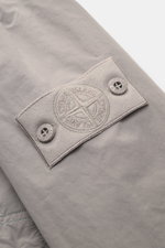 Stone Island Jacke 'Ghost Piece' hellgrau Nahaufnahme des tonalen Kompass-Badges am Oberarm, hochwertige Microfaser, softer Griff.