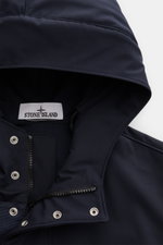 Close-up front view of the Stone Island Blouson 'Light Soft Shell-R' navy, showing the hood, two-way zip, storm flap with buttons, and high-quality softshell material. Style meets function: this soft shell jacket by STONE ISLAND features a sporty design i