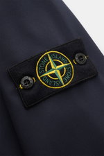 Close-up side view of the compass badge on the sleeve of the Stone Island Blouson 'Light Soft Shell-R' navy, a sporty, slim fit soft shell jacket made of high-quality microfibre with wind and water repellent properties.