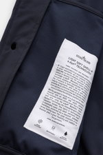 Close-up view of the Stone Island Blouson 'Light Soft Shell-R' navy showing the detailed inner label with fabric and technology info, highlighting wind and water resistance, breathability, and advanced e.dye® technology in high-quality microfibre soft she
