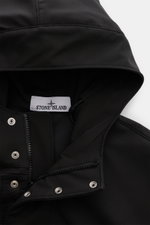 Black Stone Island Blouson 'Light Soft Shell-R' shown close-up from the front top view, featuring the hood, zipper, and snap buttons. Style meets function: This soft shell jacket by STONE ISLAND has a sporty design in three-layer functional material that 