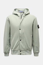 Front view of Stone Island Blouson 'Light Soft Shell-R' salbei in sage green, featuring a hood with drawstring, two-way zipper, snap wind flap, zipper pockets, elastic cuffs and hem, mesh lining, and compass badge on the upper arm. 

<p>Stil trifft Funkti